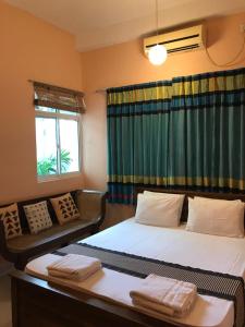 a room with two beds and a couch and a window at Araliya Suite in Nugegoda