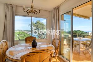 a dining room with a table and a balcony at Les brises 2 Apartament per 4 persones amb vistes a la badia de S'Agaró in S'agaro
