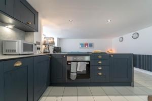 eine Küche mit blauen Schränken und einer Mikrowelle in der Unterkunft Mariner's Belle in St Ives