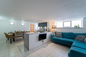 ein Wohnzimmer mit einem blauen Sofa und einer Küche in der Unterkunft Mariner's Belle in St Ives