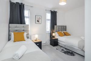 a bedroom with two beds and two windows at TMS Top Flat! Tilbury! in Tilbury
