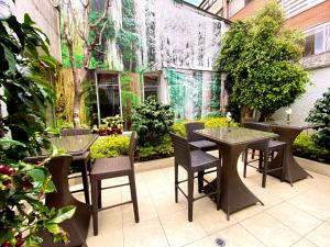 un patio al aire libre con mesas, sillas y plantas en Hotel Marbella Chico en Bogotá