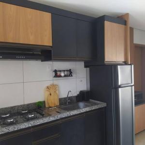 cocina con armarios negros y nevera de acero inoxidable en Condomínio Villamares en Luis Correia
