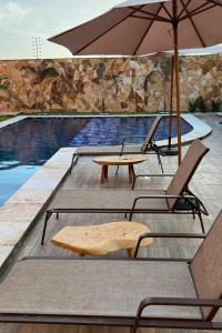 una piscina con 2 mesas y una sombrilla en Condomínio Villamares en Luis Correia