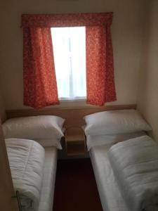 2 Betten in einem kleinen Zimmer mit Fenster in der Unterkunft Ingoldmells - Millfields D13 in Ingoldmells