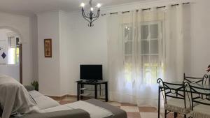 a living room with a couch and a tv and a window at La casa del parque in Arcos de la Frontera