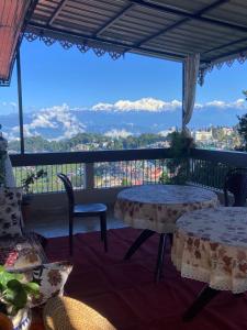 a balcony with tables and chairs and a view of mountains at Indivar Homestay in Darjeeling
