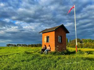 two people sitting in a small house in a field at Sovgodt Nyord - Primitiv overnatning in Nyord