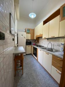 eine Küche mit weißen Schränken, einer Spüle und einem Tisch in der Unterkunft Casa Da Simone in Melissano