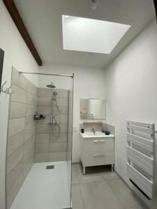 a white bathroom with a shower and a sink at L'Avison in Bruyères