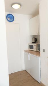 eine Küche mit einer Mikrowelle und einer Uhr an der Wand in der Unterkunft T2 Proche Capelan -parking privé gratuit - wifi in Bandol
