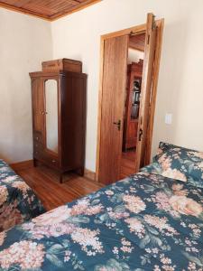 a bedroom with two beds and a dresser and a door at Solar dos Tios in São Thomé das Letras