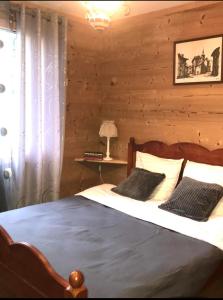 1 dormitorio con 1 cama con pared de madera en Chalet des Fées , 2 chambre ,70m2 ,navette gratuite, en Les Avanchers