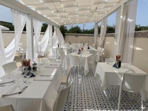 un comedor con mesas blancas y sillas blancas en Bono Vacanze Villa Maragani Charme & Relax, en Sciacca