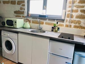een keuken met een wastafel en een magnetron bij Cocooning little house in french Vexin in Us