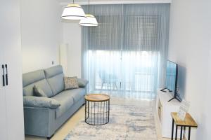 ein Wohnzimmer mit einem blauen Sofa und einem Fenster in der Unterkunft Anka Beach Apartment Patacona in Valencia