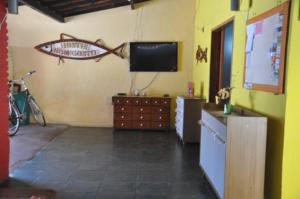 a living room with a television and a table with a fish on the wall at HOSTEL Bom Gosto in Canavieiras