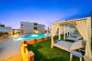 een villa met een zwembad en een patio bij Rainbow Apartments in Stalida