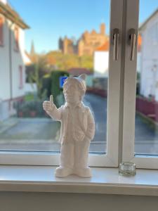 une figurine blanche de chat debout sur un rebord de fenêtre dans l'établissement Ferienwohnung Bett & Burg, à Wertheim