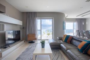 a living room with a leather couch and a television at Waters-Edge Complex in Marsaskala