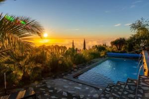 a swimming pool with a sunset in the background at Panorama Suite El Mirador in Puntagorda