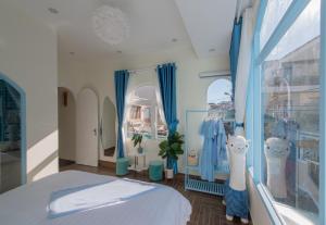 1 dormitorio con cortinas azules, 1 cama y ventana en Moc Thach Blue House DaLat, en Da Lat