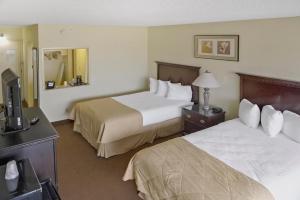 a hotel room with two beds and a television at Economy Hotel Plus Wichita in Wichita