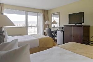 a hotel room with two beds and a flat screen tv at Economy Hotel Plus Wichita in Wichita