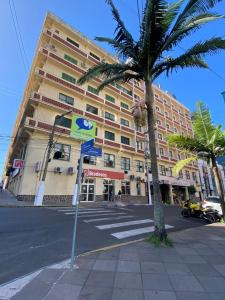 een groot gebouw met een palmboom ervoor bij Grande Hotel Torres in Torres