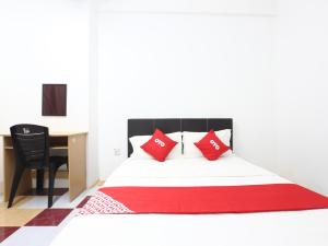 een slaapkamer met een bed met rode kussens en een bureau bij Kb Rest Inn-Deluxe Queen in Kota Bharu