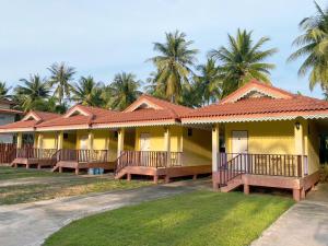 a row of yellow houses with palm trees in the background at The An Ant บ้านพัก&โฮมสเตย์ in Sam Roi Yot