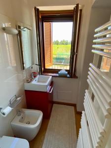 a bathroom with a sink and a toilet and a window at Cascina la Barona in Savigliano