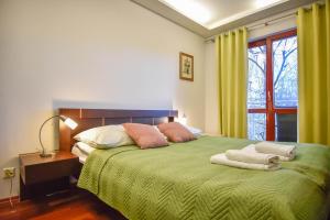sypialnia z zielonym łóżkiem z poduszkami i oknem w obiekcie Apartamenty na Wyspie - Róża Wiatrów w Świnoujściu