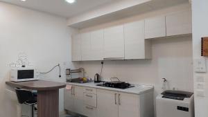 una pequeña cocina con armarios blancos y microondas en Greenfield Regency Comfort Suite - Wifi 4pax Paradigm & Sutera, en Johor Bahru