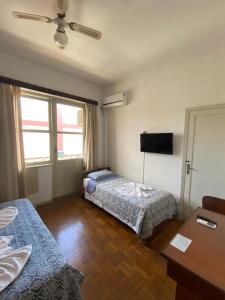 a hotel room with two beds and a flat screen tv at Grande Hotel Torres in Torres