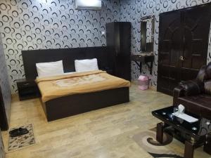 a bedroom with a bed and a chair and a couch at Karachi Guest House & Couple Hotel in Karachi