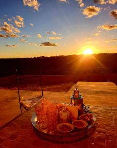 a plate of food on a table with the sunset in the background at Maison d'hôtes IZZA in El Kelaa des Mgouna