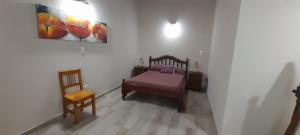 1 dormitorio con 1 cama, 1 silla y 1 pintura en Departamento La Tercera en San Clemente del Tuyú