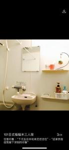 uma casa de banho branca com um lavatório e um espelho em 桜宿-ダブルベッドの小さなガーデンルーム em Tóquio