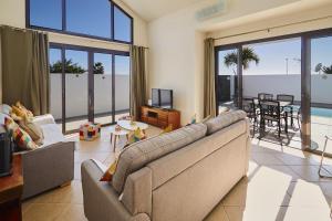 a living room with a couch and a tv at Villa Cantium - LH101 By Villas Now Ltd in Playa Blanca