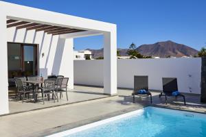 un patio con tavolo e sedie accanto alla piscina di Villa Cantium - LH101 By Villas Now Ltd a Playa Blanca