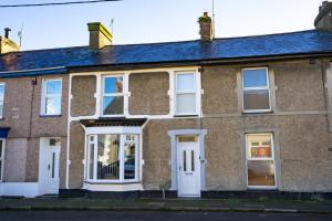 una antigua casa de ladrillo con puertas y ventanas blancas en Newly-renovated, mid-terrace cottage in Porthmadog en Porthmadog