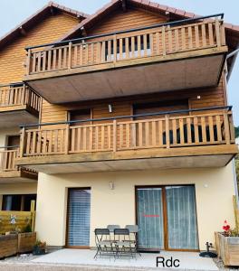 a house with a deck with tables and chairs at Les balcons de la haie griselle in Gérardmer