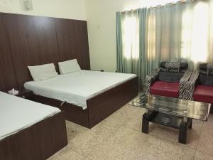 a room with two beds and a glass table at Karachi Guest House & Couple Hotel in Karachi