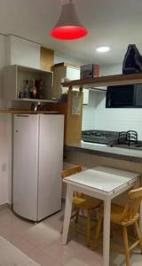 uma cozinha com um frigorífico e uma mesa com cadeiras em Apartamento bairro Praia do Canto na Reta da Penha em Vitória