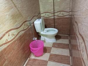 Un baño con inodoro y un cubo rosa. en Karachi Guest House & Couple Hotel, en Karachi 16 fotos más