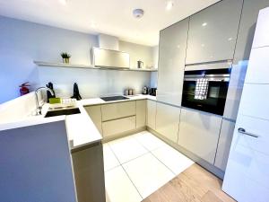 a kitchen with white cabinets and a stove top oven at Beautiful New 2 Bedroom Apartment - Next to the Beach - Great Location - FREE Parking - Fast WiFi - Smart TV - sleeps up to 4! Close to Purbeck, Corfe Castle, Sandbanks, Poole & Bournemouth in Swanage