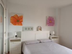 um quarto com uma cama branca com duas flores na parede em OceanView Apartment em La Manga del Mar Menor