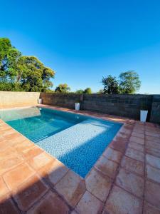 a swimming pool in a backyard with a brick wall at Cabañas Aranderay in Puerto Esperanza