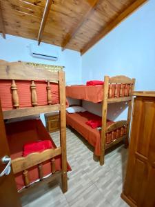 a room with two bunk beds with red sheets at Cabañas Aranderay in Puerto Esperanza